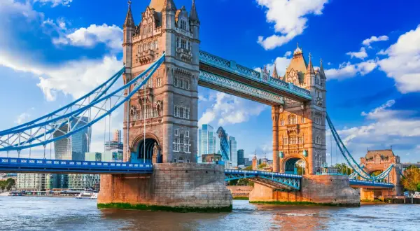 Tower Bridge w Londynie nad Tamizą, z nowoczesnymi wieżowcami w tle.